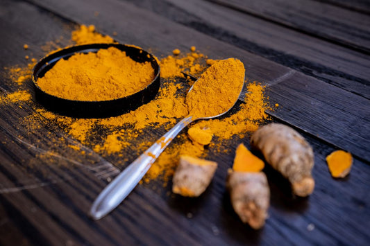 Whole turmeric root with ground turmeric powder on wood