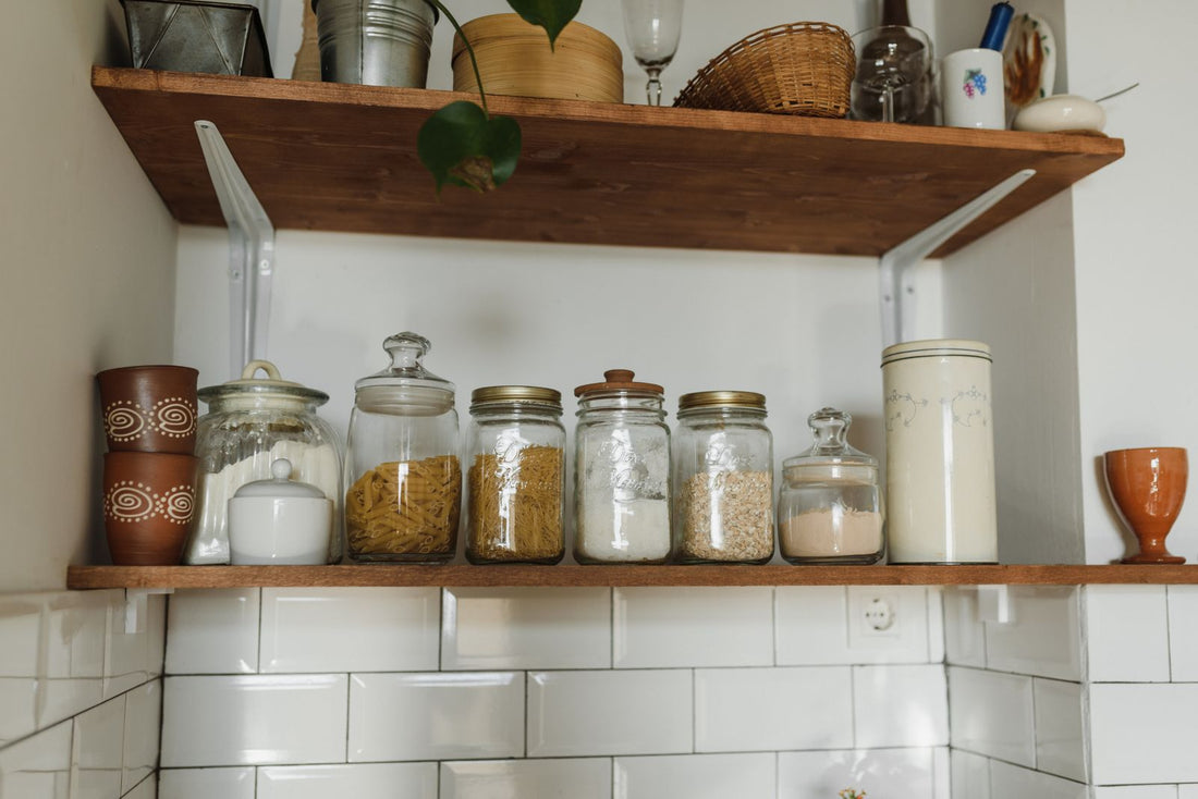 Glass storage jars arranged on an open wooden kitchen shelf