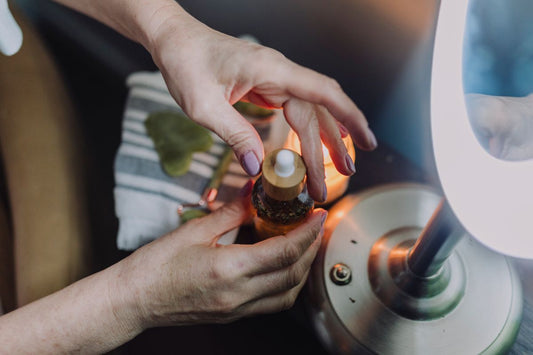 Person holding a dropper bottle near a lamp