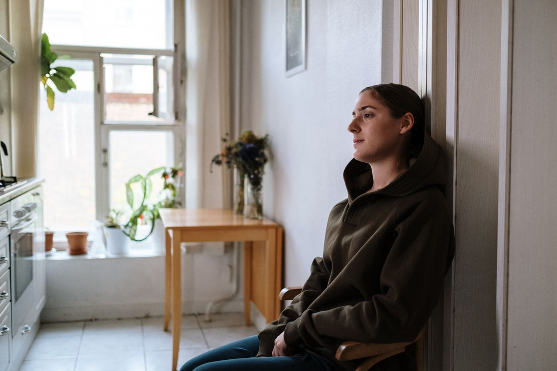 A person sitting by a window looking tired and unfocused