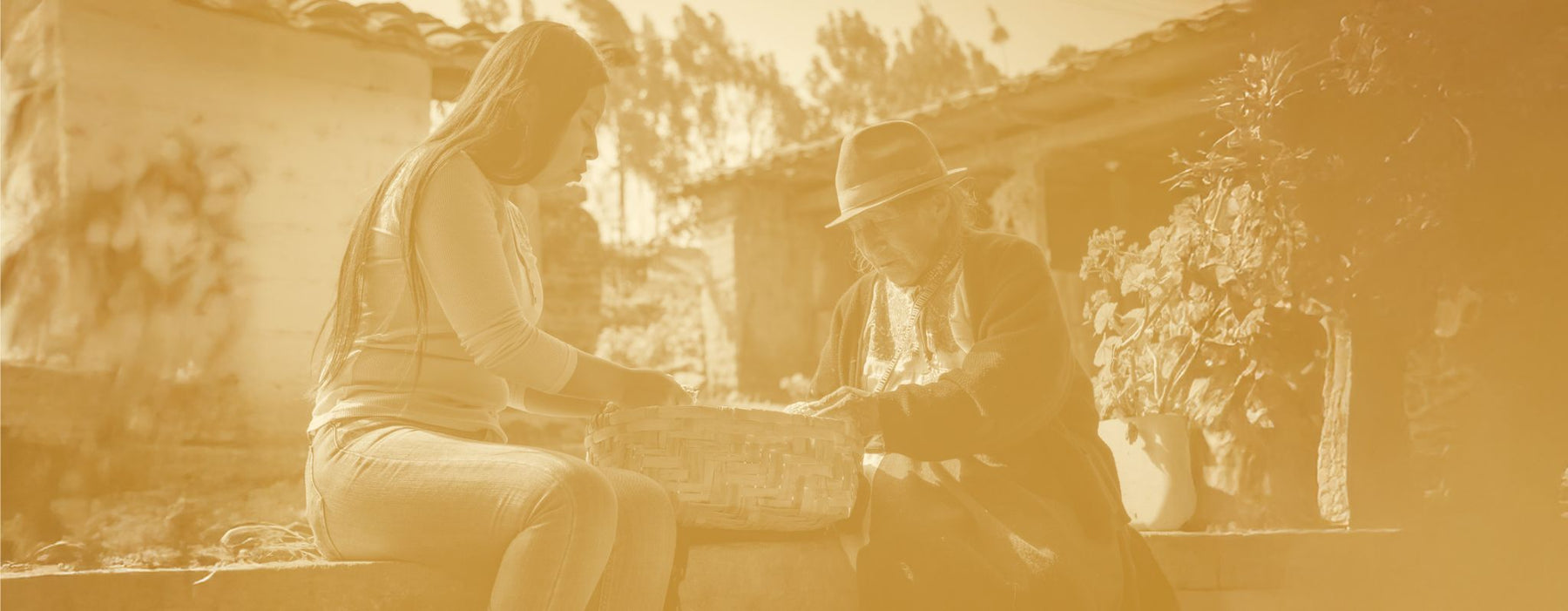 Two people sorting harvested goods together outside a home.