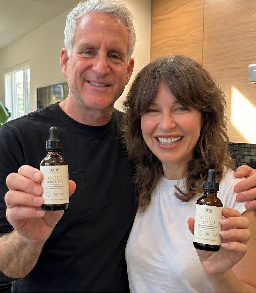 A man and a woman each holding a bottle of Logic Lion's Mane tincture from Of The Ancients